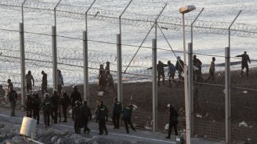 Las fuerzas españolas de seguridad e inmigrantes a ambos lado de la valla de Ceuta