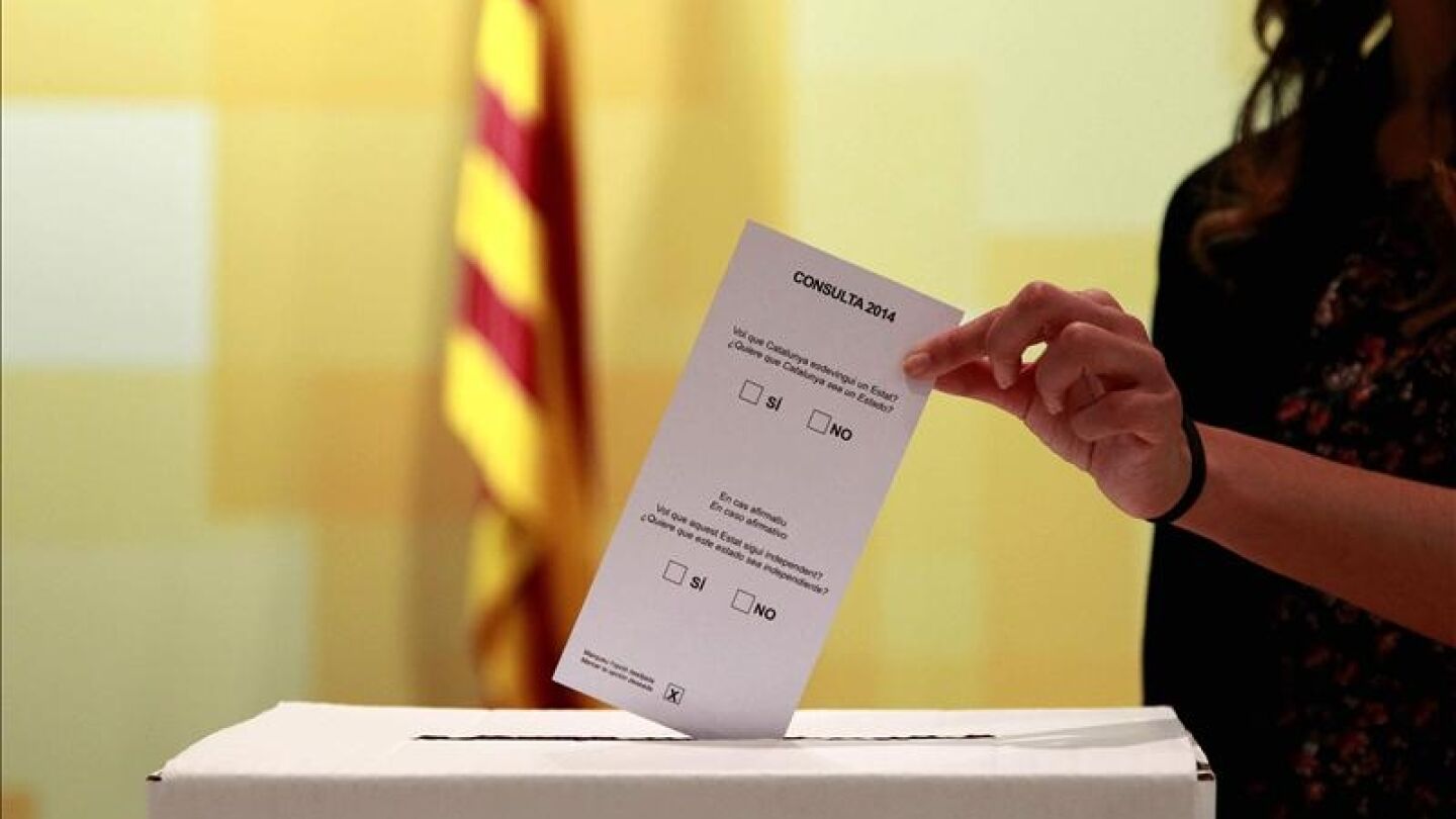 Una persona introduce una papeleta en una urna el 9N