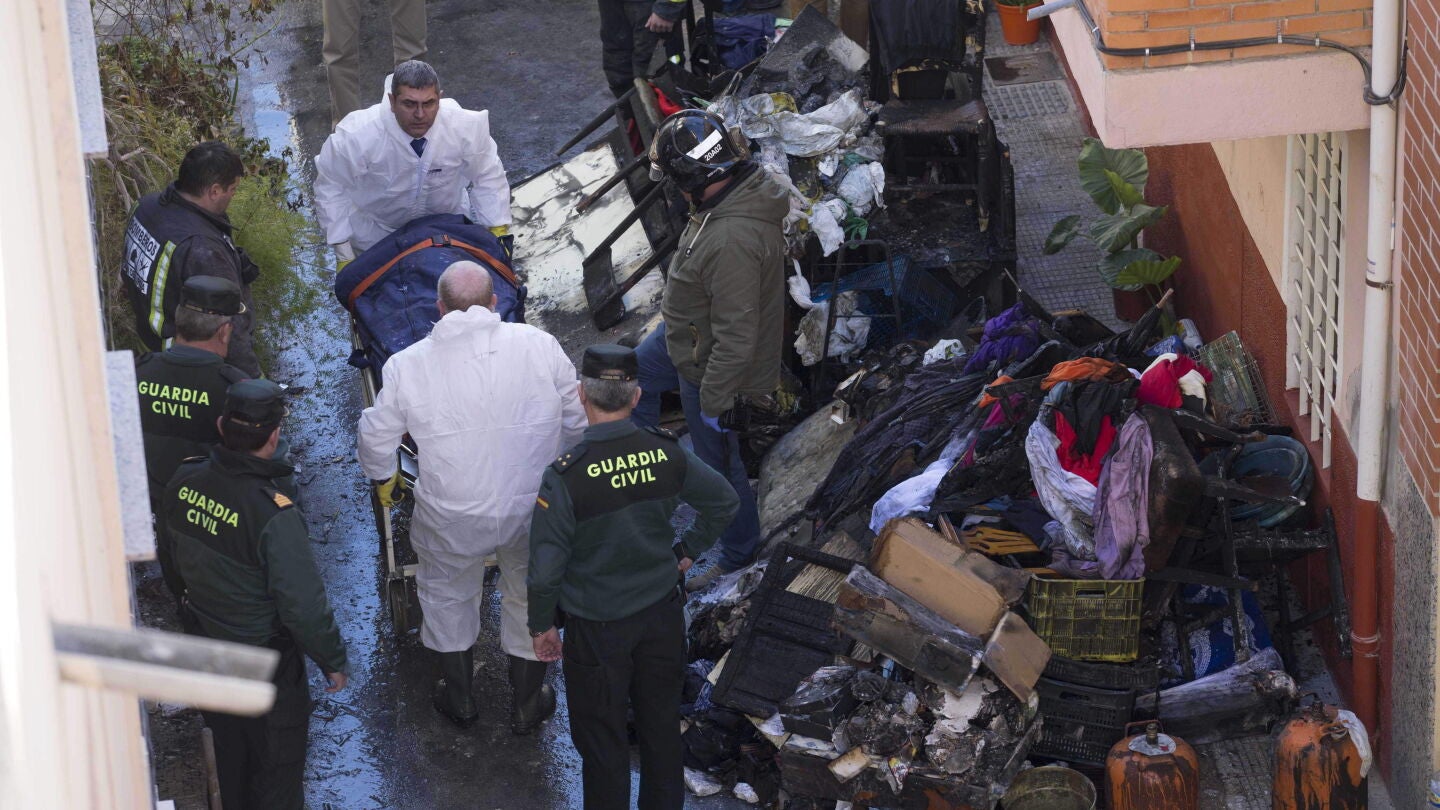 Efectivos de los servicios funerarios trasladan el cuerpo de uno de los tres fallecidos en el incendio.