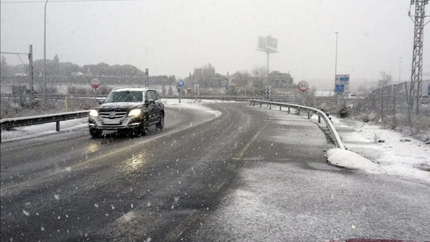 Un vehículo circula por una carretera nevada Un vehículo circula por una carretera nevada