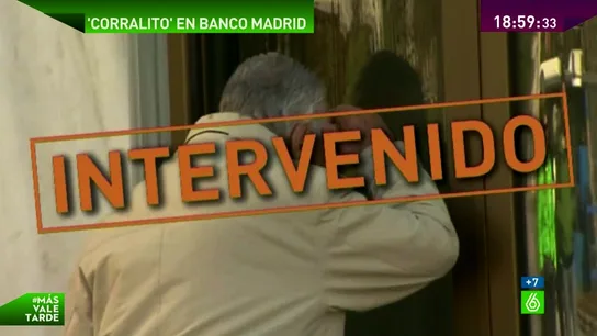 Un hombre mira por la puerta de Banco Madrid Un hombre mira por la puerta de Banco Madrid
