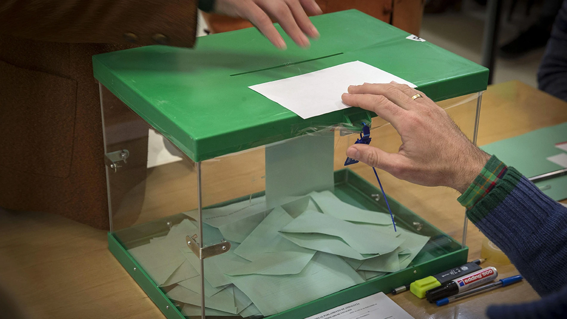 Un votante ejerce su derecho introduciendo la papeleta en la urna en un colegio electoral en Sevilla