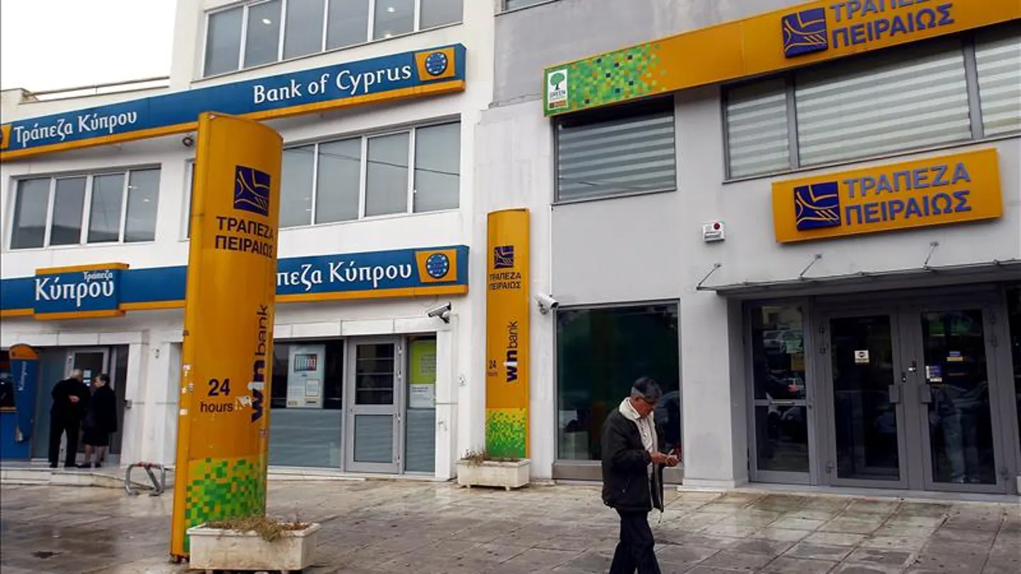 Un hombre pasa junto a una sucursal del Banco de Chipre y del Banco Piraeus, en Atenas Un hombre pasa junto a una sucursal del Banco de Chipre y del Banco Piraeus, en Atenas
