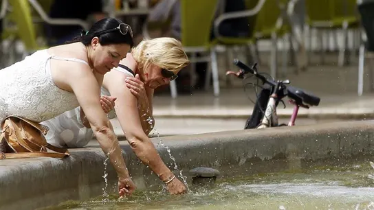 Dos mujeres se refrescan en una fuente Dos mujeres se refrescan en una fuente