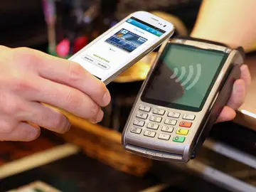 Una persona pagando con su teléfono móvil Una persona pagando con su teléfono móvil