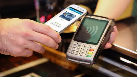 Una persona pagando con su teléfono móvil Una persona pagando con su teléfono móvil
