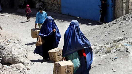 Dos mujeres caminan con cajas en la mano Dos mujeres caminan en Afganistán