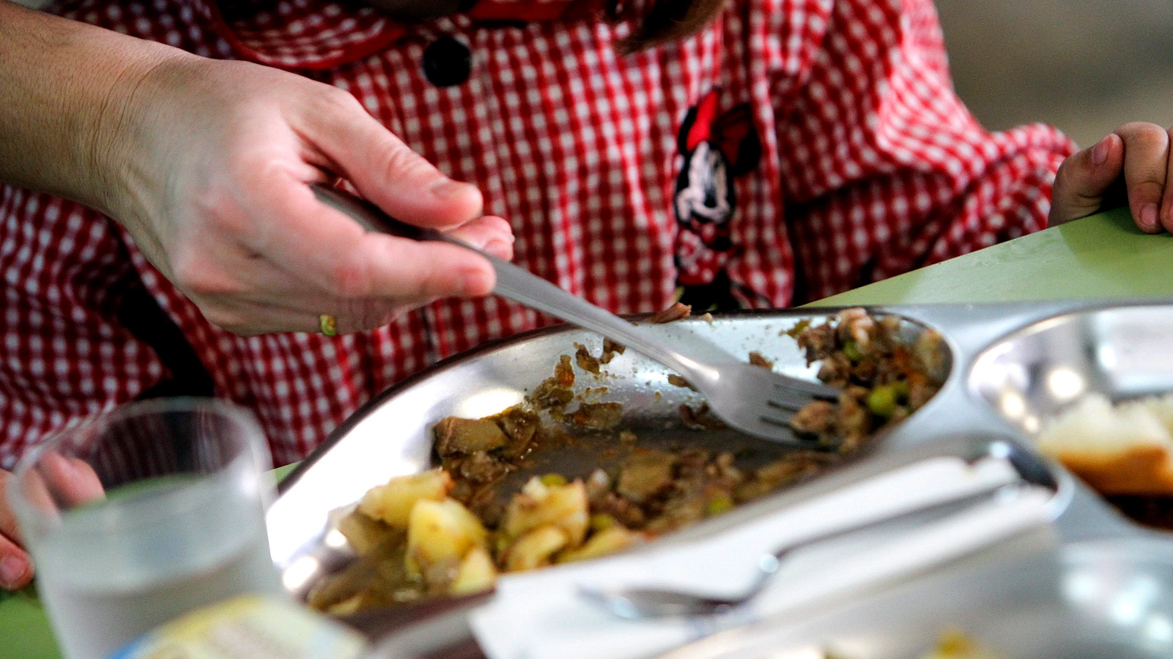 Una niña almorzando en un comedor escolar.