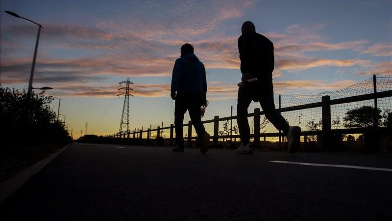 Fotografía facilitada de un par de inmigrantes que se dirigen al túnel del Canal de la Mancha