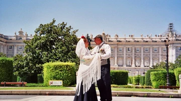 Dos personas bailan el tradicional chotis madrileño frente al Palacio Real de Madrid.