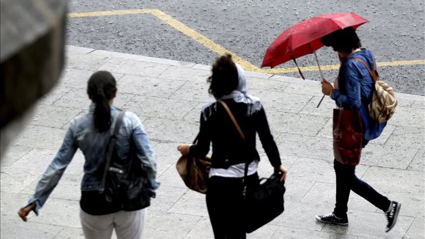 Paseantes tratan de cubrirse de las fuertes lluvias con paraguas Paseantes tratan de cubrirse de las fuertes lluvias con paraguas