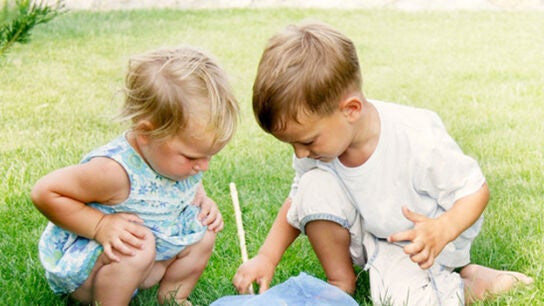 Imagen de dos ni&ntilde;os jugando en el c&eacute;sped
