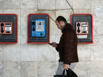 Un peatón camina mirando su teléfono móvil Un peatón camina mirando su teléfono móvil