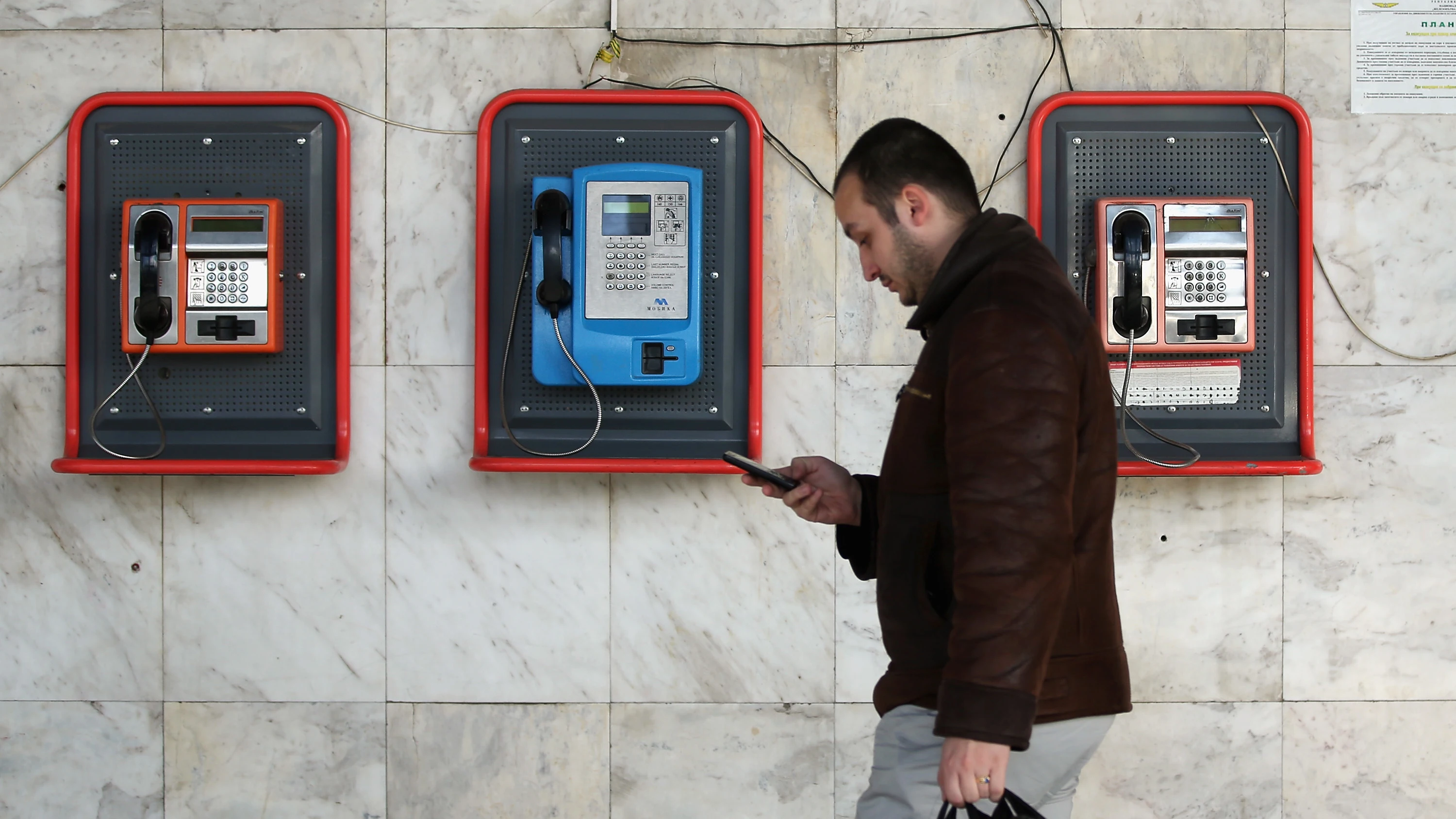 Un peatón camina mirando su teléfono móvil