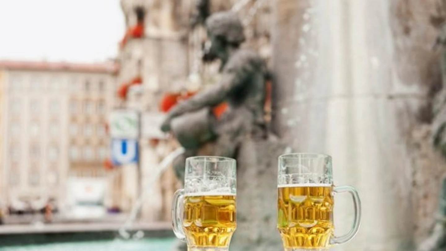 Dos jarras de cerveza frente a una fuente Dos jarras de cerveza frente a una fuente