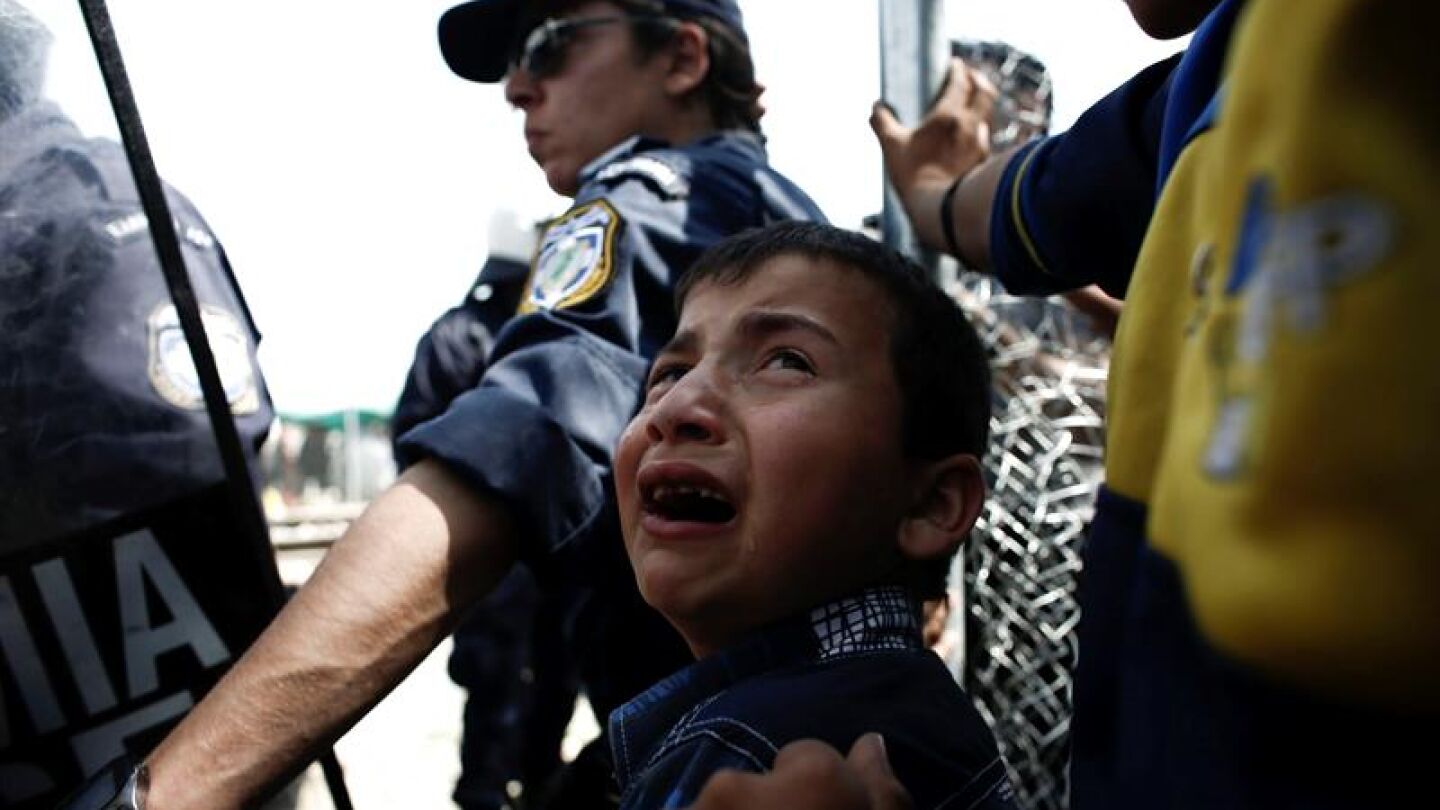 Un ni&ntilde;o refugiado llora junto a un Polic&iacute;a