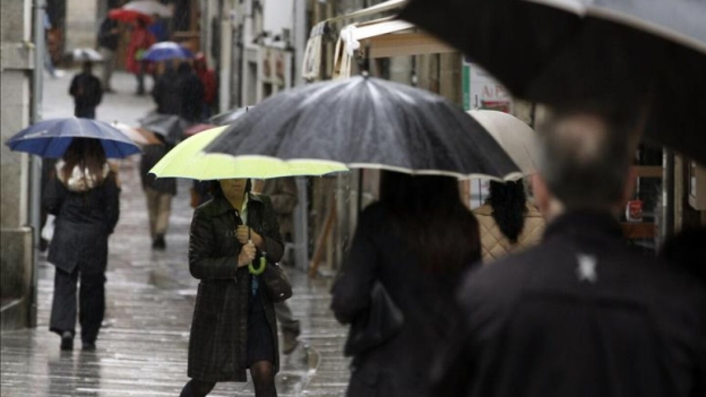  Varias personas se protegen de la lluvia con paraguas 