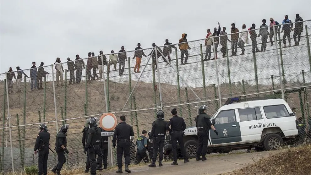 Inmigrantes sobre la valla de Melilla