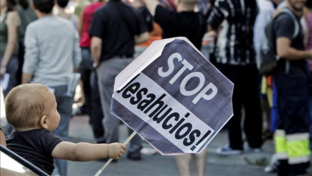 Un niño sostiene un cartel de Stop desahucios (Archivo)
