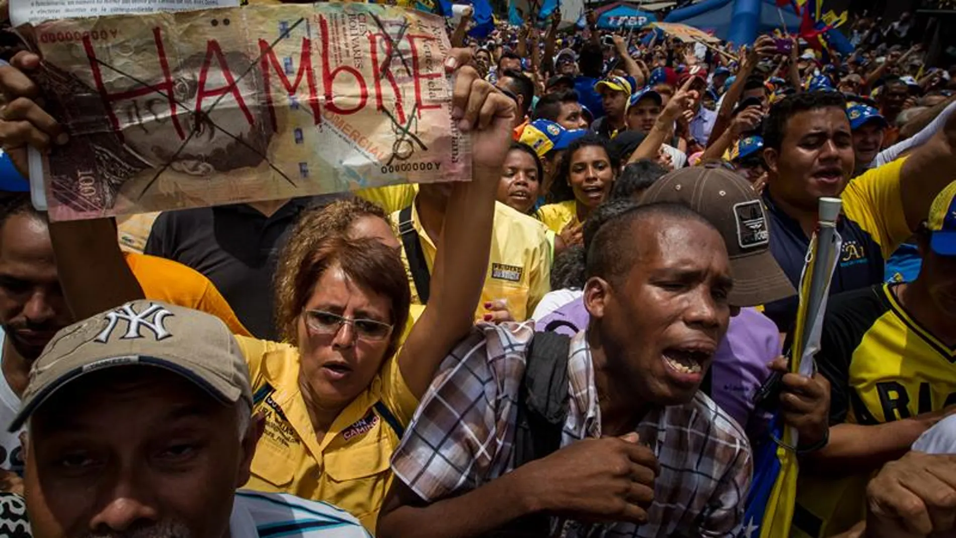 Una manifestante sostiene un letrero con la palabra "Hambre" en una protesta contra el Gobierno venezolano