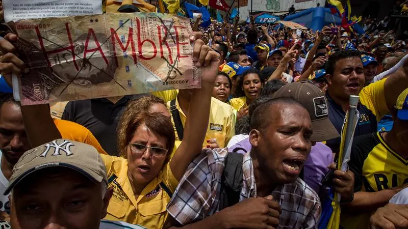 Una manifestante sostiene un letrero con la palabra "Hambre" en una protesta contra el Gobierno venezolano