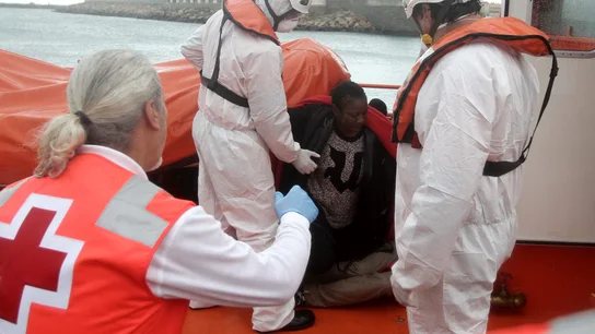Personal de Cruz Roja ayudan a levantarse a unos inmigrantes que viajaban en una patera y que fueron rescatados por Salvamento Marítimo Personal de Cruz Roja ayudan a levantarse a unos inmigrantes que viajaban en una patera y que fueron rescatados por Salvamento Marítimo