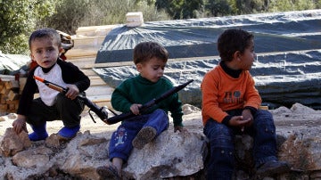 Niños sirios sostienen armas de juguete en un campo de refugiados