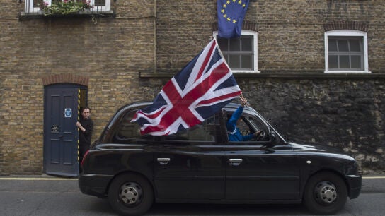 Un taxista ondea una bandera brit&aacute;nica en una calle con una bandera europea