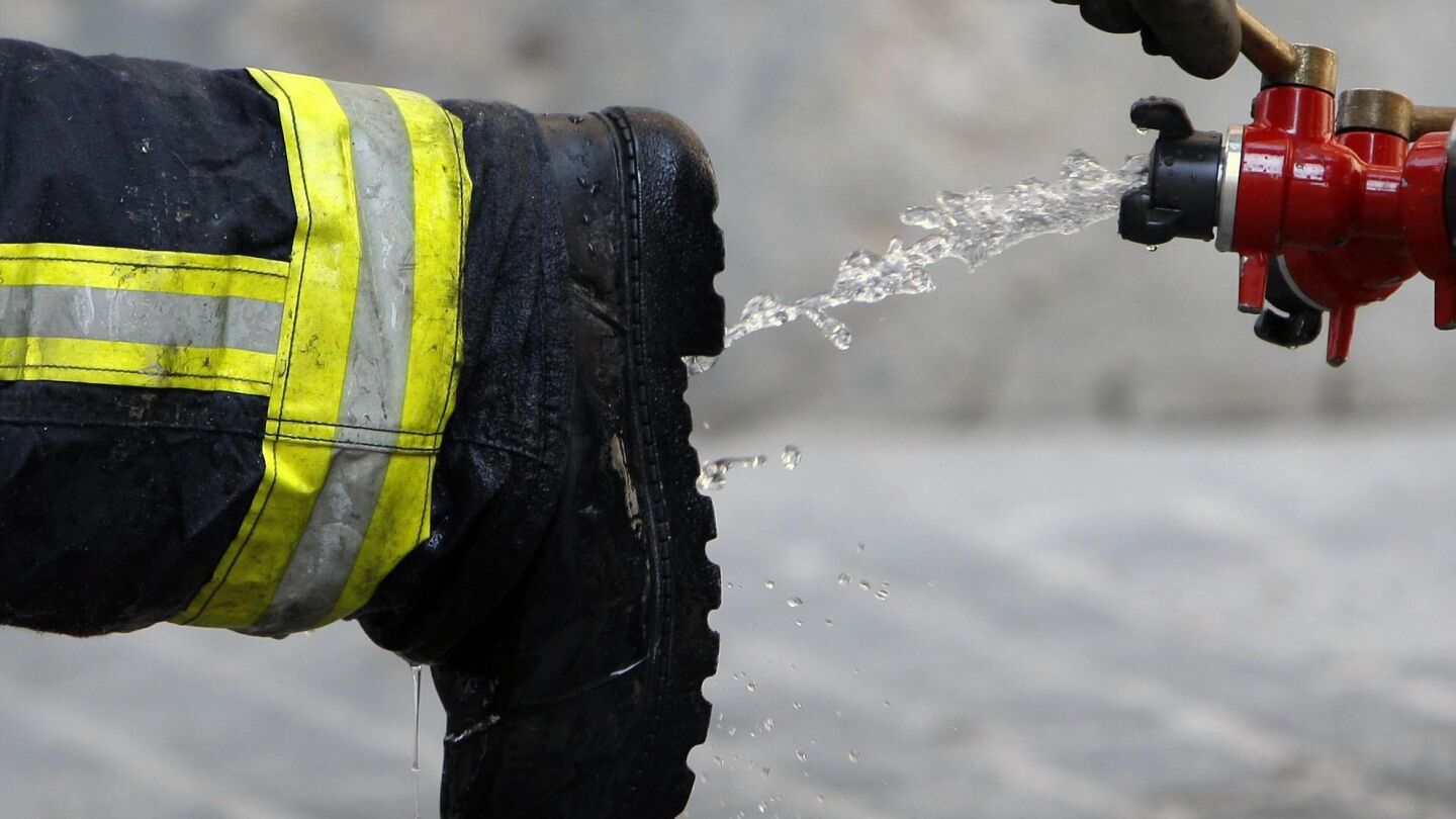 Un bombero limpia sus botas tras declarar extinguido un incendio