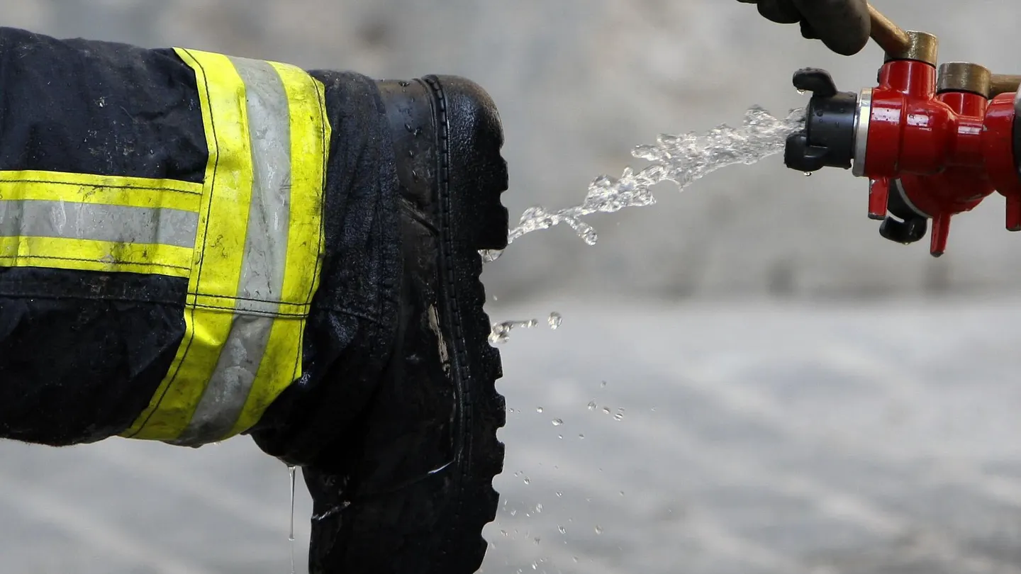 Un bombero limpia sus botas tras declarar extinguido un incendio Un bombero limpia sus botas tras declarar extinguido un incendio