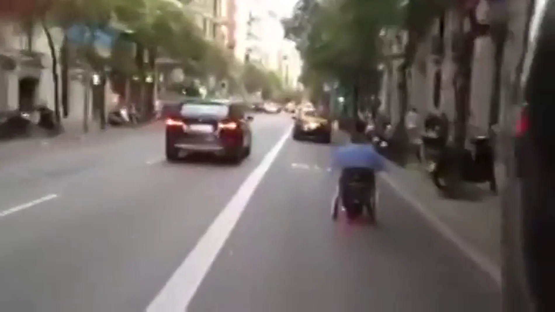 Frame 10.353453 de: Un hombre en silla de ruedas se desplaza a toda velocidad por las calles de Barcelona