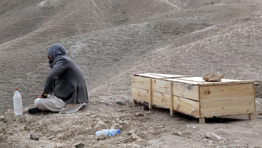 Un hombre sentado junto a un féretro en Afganistán 