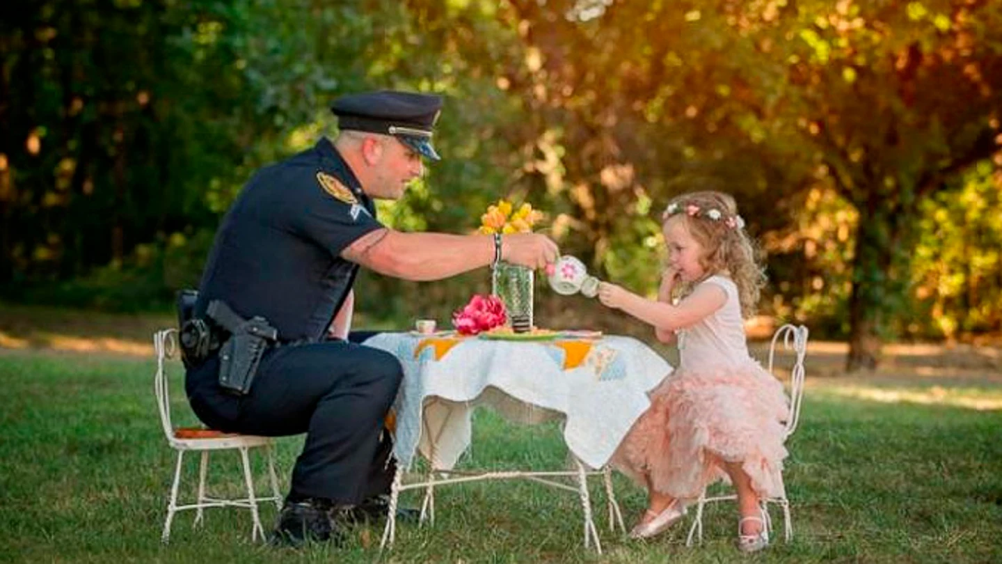 La pequeña de dos años toma el té con el Policía que le salvó la vida. La pequeña de dos años toma el té con el Policía que le salvó la vida.