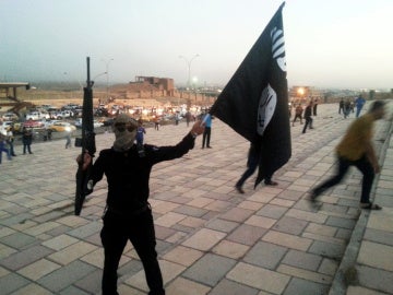 Un combatiente de Daesh sostiene una bandera y un arma en una calle de Mosul Un combatiente de Daesh sostiene una bandera y un arma en una calle de Mosul