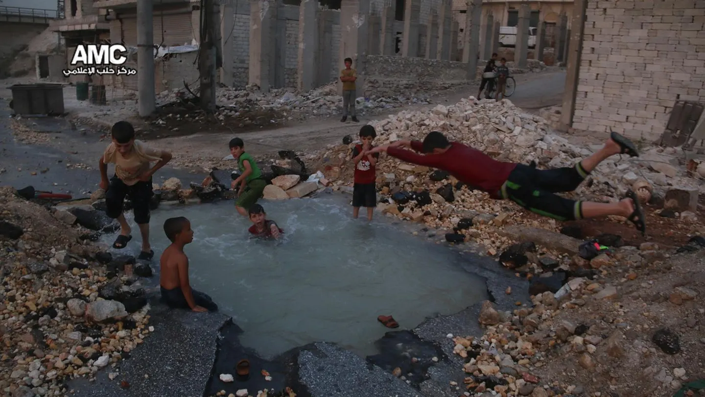 Un grupo de niños sirios juega en torno al cráter de una bomba convertido en piscina en Alepo Un grupo de niños sirios juega en torno al cráter de una bomba convertido en piscina en Alepo