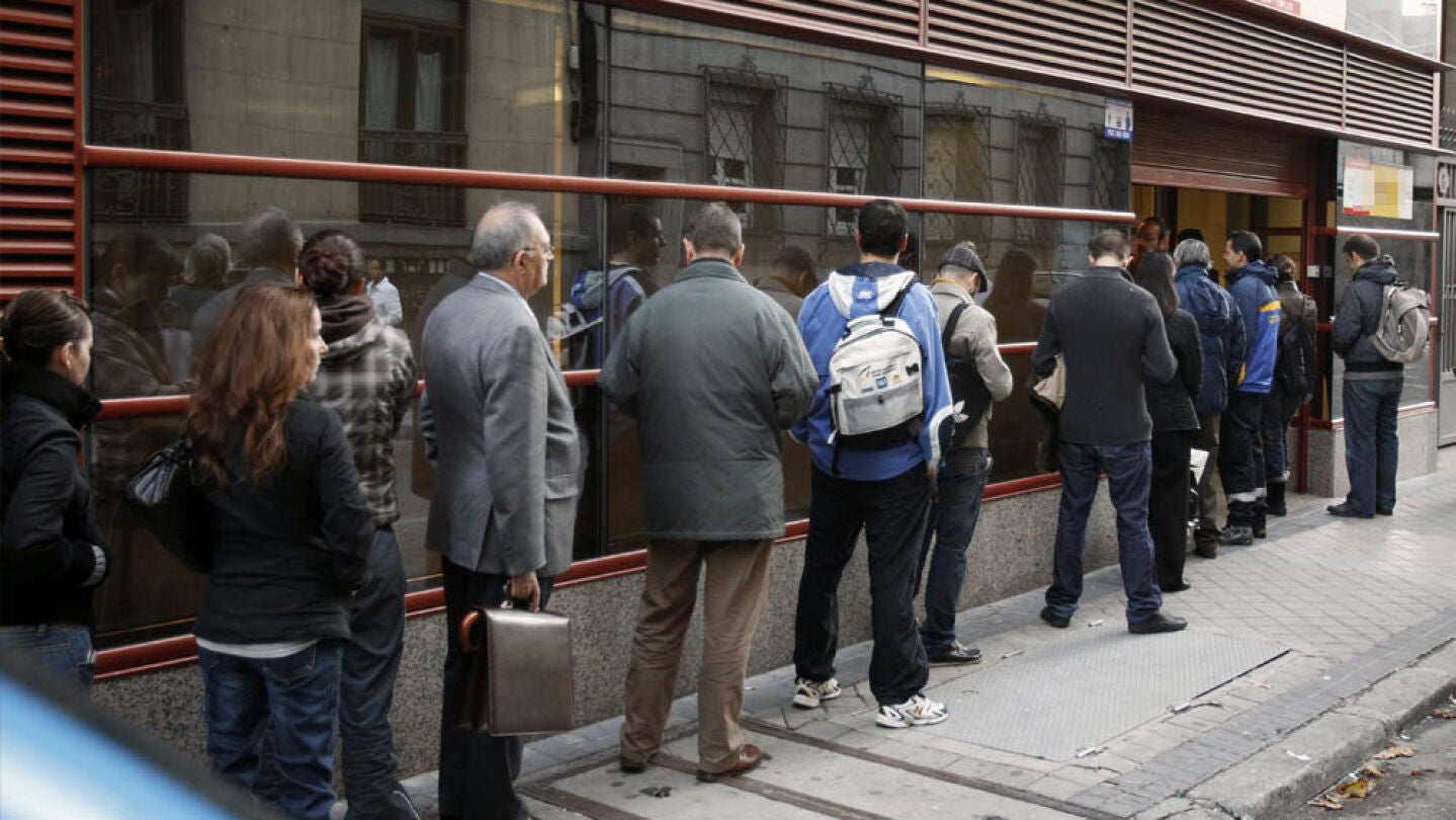Varias personas hacen fila frente a una oficina de empleo