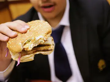 Un colegial come una hamburguesa para almorzar Un colegial come una hamburguesa para almorzar