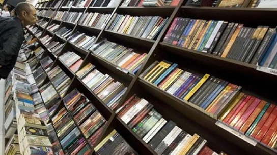 Un hombre ojea varios libros en una librería Un hombre ojea varios libros en una librería