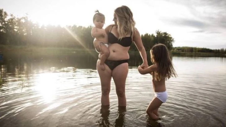 Una madre juega con sus hijos en un lago durante la sesión fotográfica