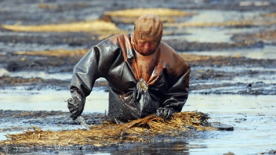 Un trabajador limpiando petróleo Un trabajador limpiando petróleo