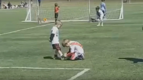 Un niño ayuda a otro a atarse la bota durante un partido en Argentina Un niño ayuda a otro a atarse la bota durante un partido en Argentina