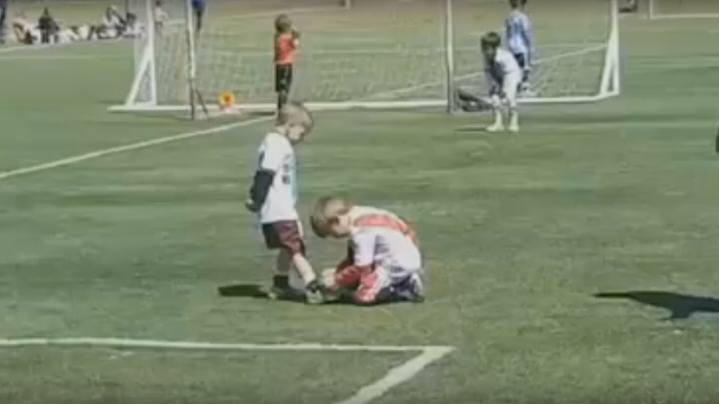 Un ni&ntilde;o ayuda a otro a atarse la bota durante un partido en Argentina