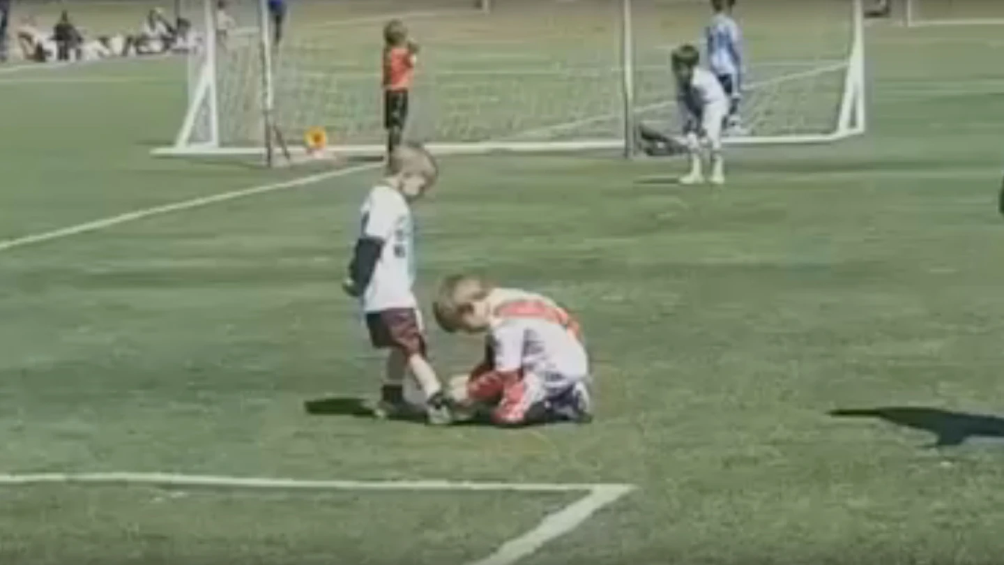 Un niño ayuda a otro a atarse la bota durante un partido en Argentina Un niño ayuda a otro a atarse la bota durante un partido en Argentina