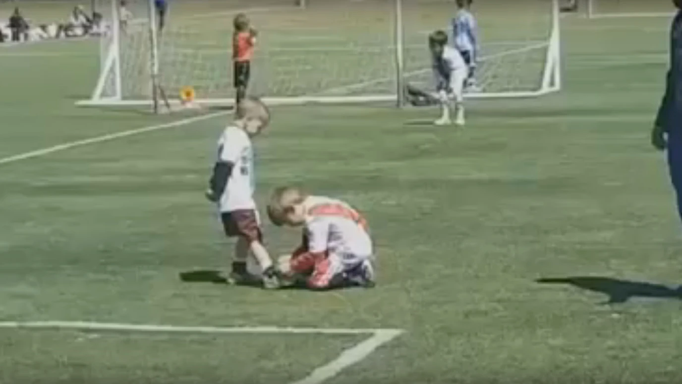 Un niño ayuda a otro a atarse la bota durante un partido en Argentina