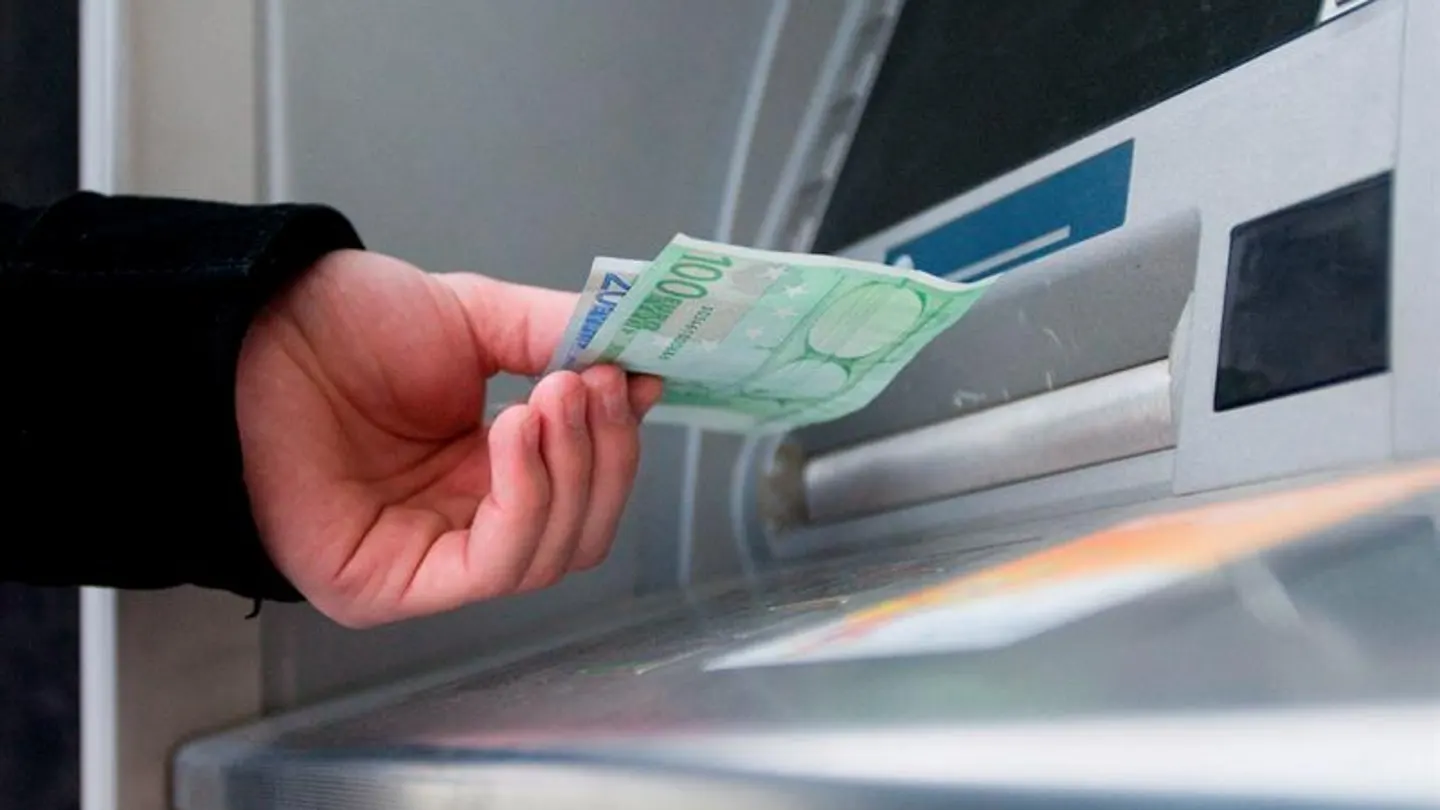 Un hombre saca euros de un cajero automático Un hombre saca euros de un cajero automático