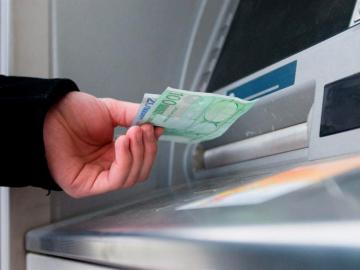 Un hombre saca euros de un cajero automático Un hombre saca euros de un cajero automático