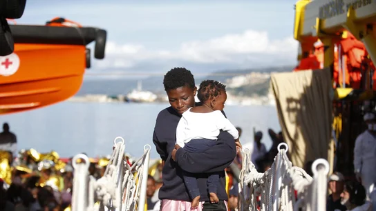 Una mujer sujeta a un bebé tras ser rescatados ambos Una mujer sujeta a un bebé tras ser rescatados ambos