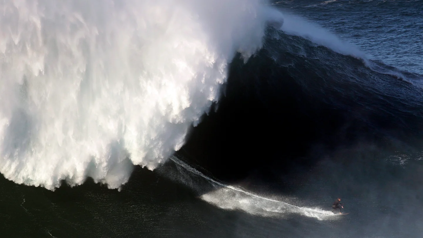 Un surfista desciende una ola en Nazaré Un surfista desciende una ola en Nazaré