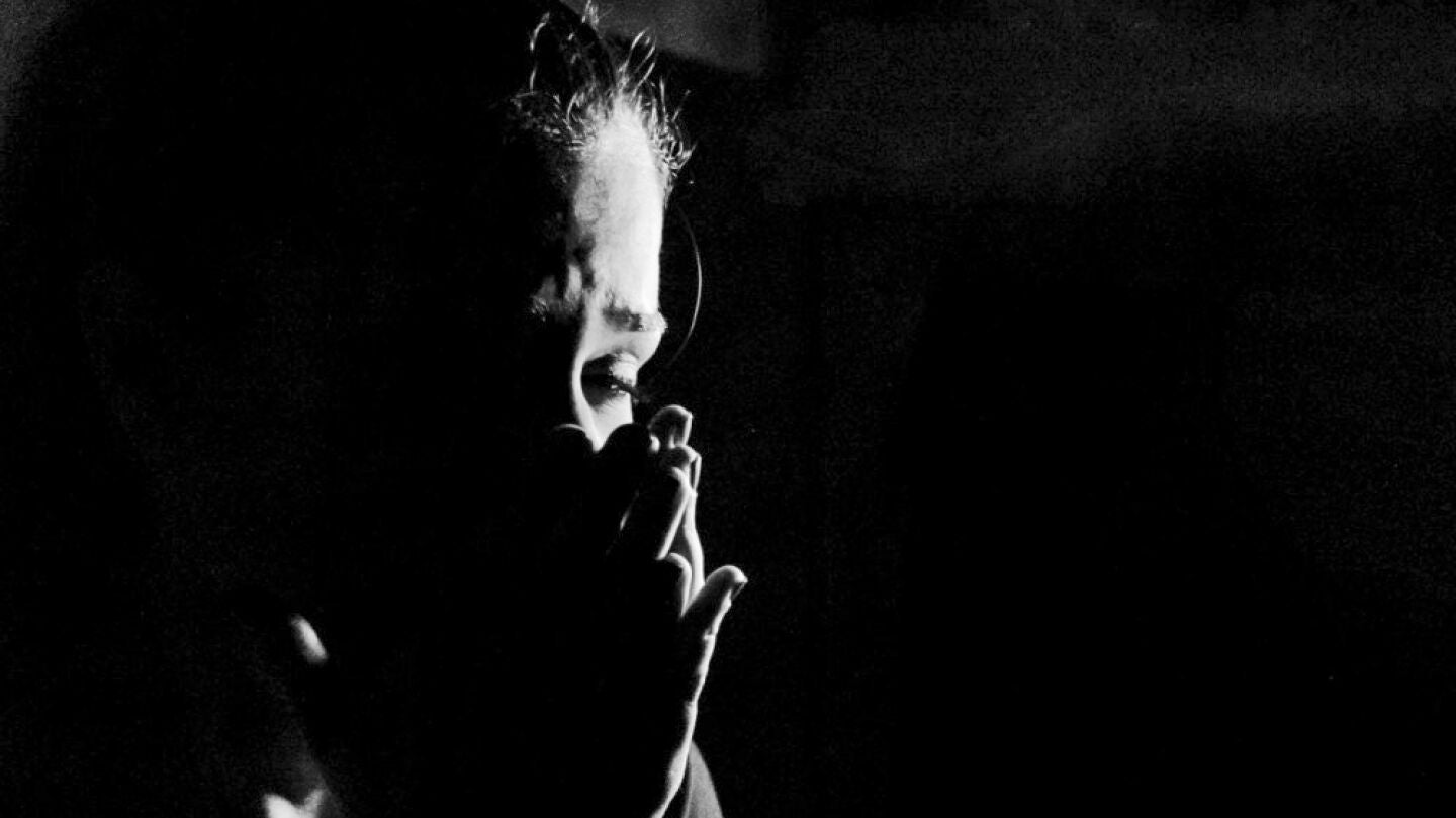Imagen de archivo de una mujer con las manos sobre la cara con un fondo negro
