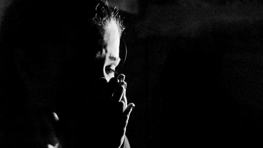 Imagen de archivo de una mujer con las manos sobre la cara con un fondo negro